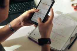 Person using a smartphone over a notebook